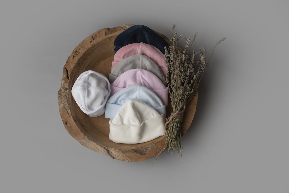 Gorros lisos com dobra larga em várias cores, num cesto; à venda em branco e baunilha
